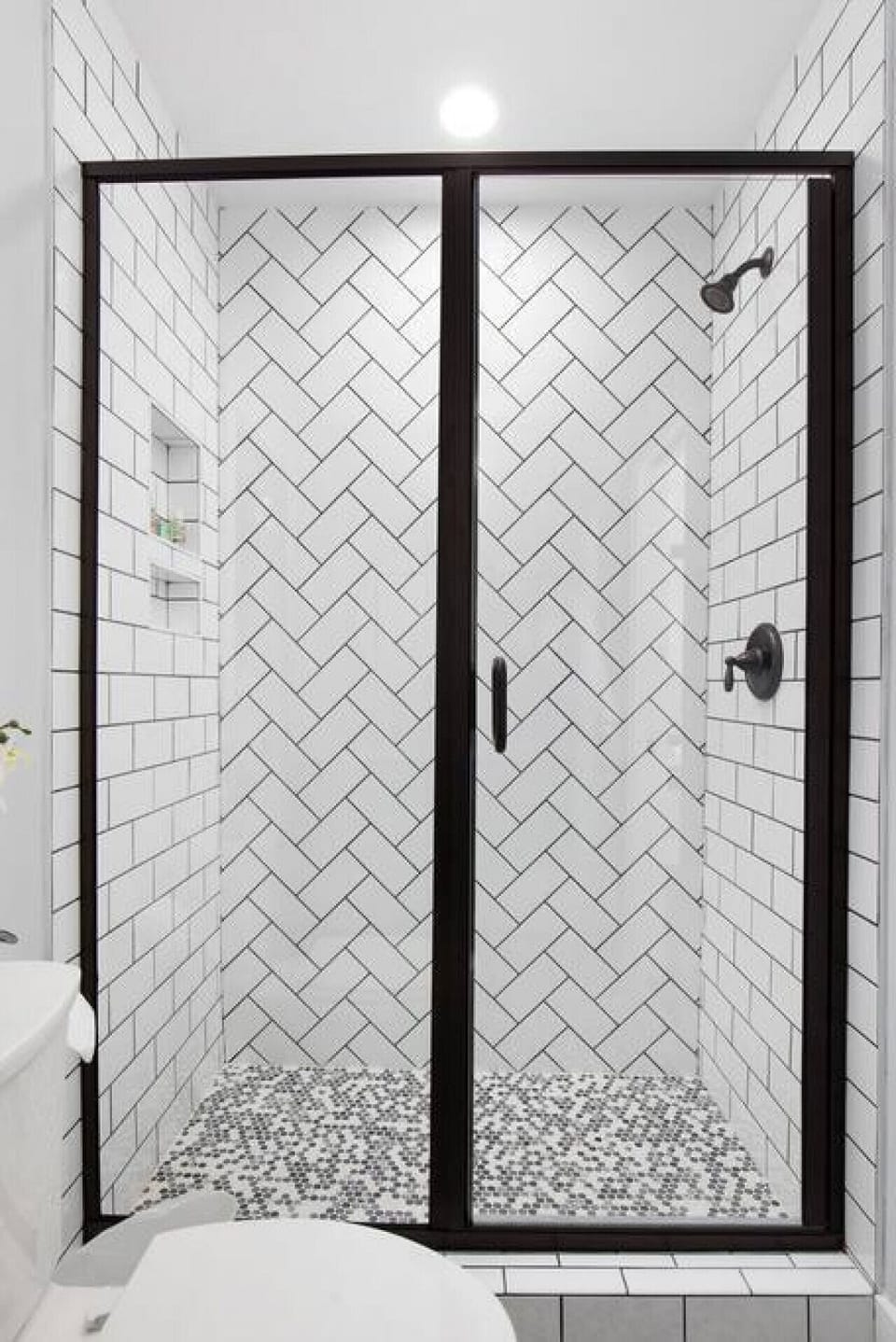 Walk-in shower with herringbone tile in the second full bathroom.