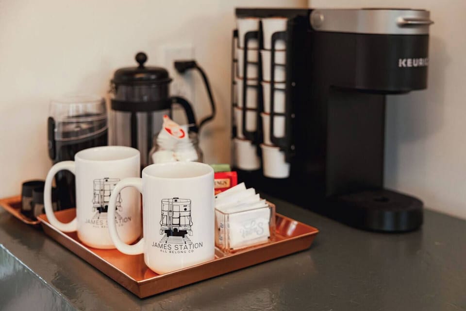 Coffee station includes a Keurig with coffee k-cups + empty k-cups for your own favorite ground coffee, french press, coffee grinder, teas, sugar, half & half, etc. All the goodness in a branded James Station mug!