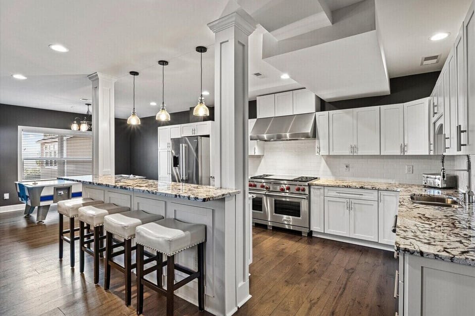 Ground-level: Chef kitchen #2 - Delight in this stunning second kitchen with a game room, featuring a spacious island, modern appliances, and stylish decor. Perfect for family fun and cooking—book your vacation rental now!