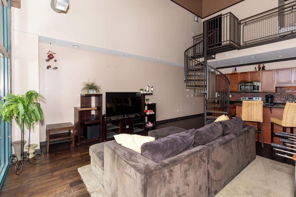 Unwind in your spacious living room featuring modern furnishings, entertainment center, and elegant spiral staircase leading to your private loft.