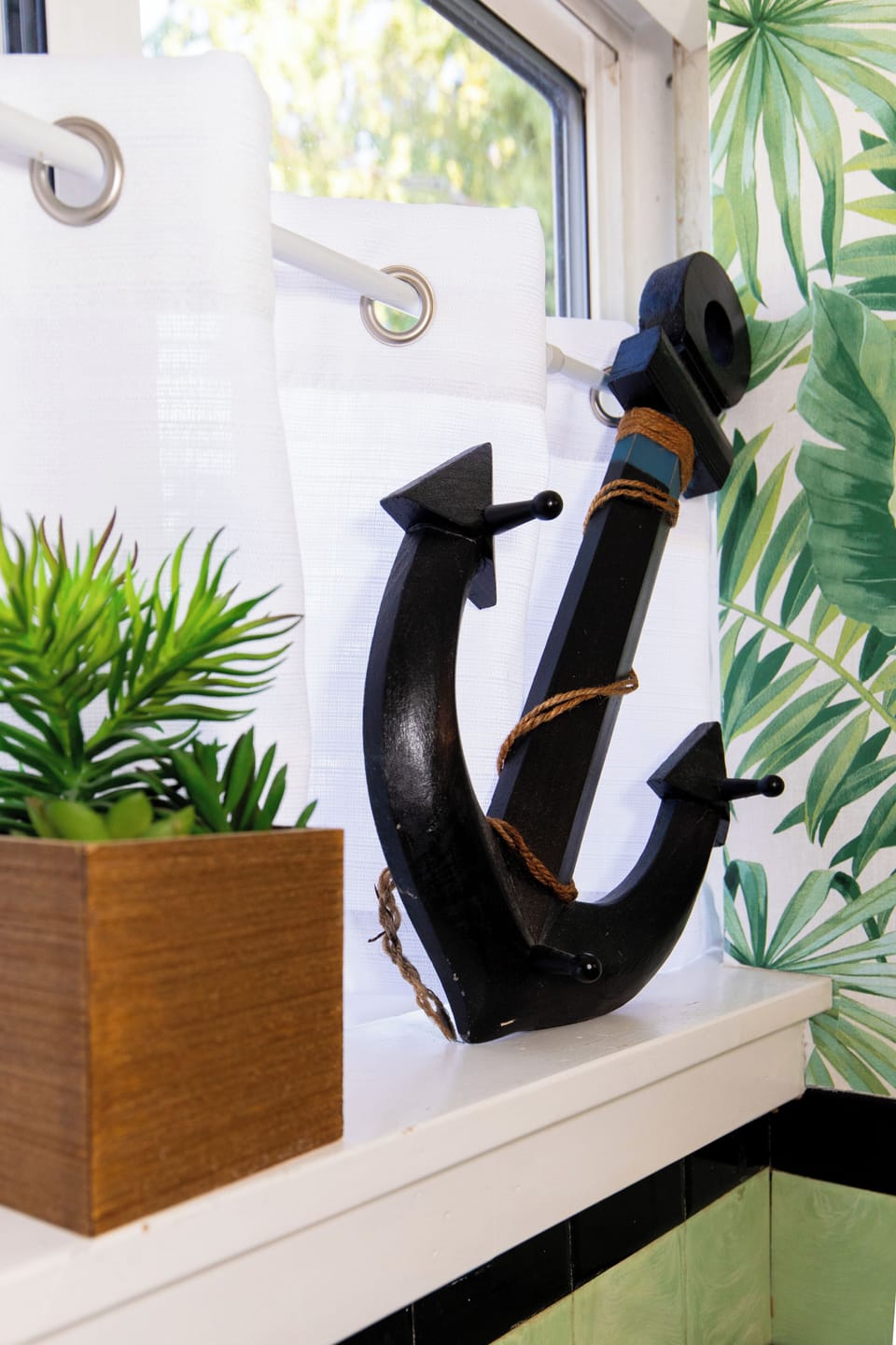 Nautical charm meets tropical vibes in your bright window nook, where decorative elements create a coastal retreat.