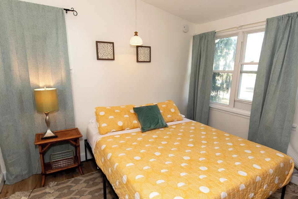 Drift off in your cozy bedroom featuring cheerful golden bedding and soft natural light streaming through sage-green curtains.