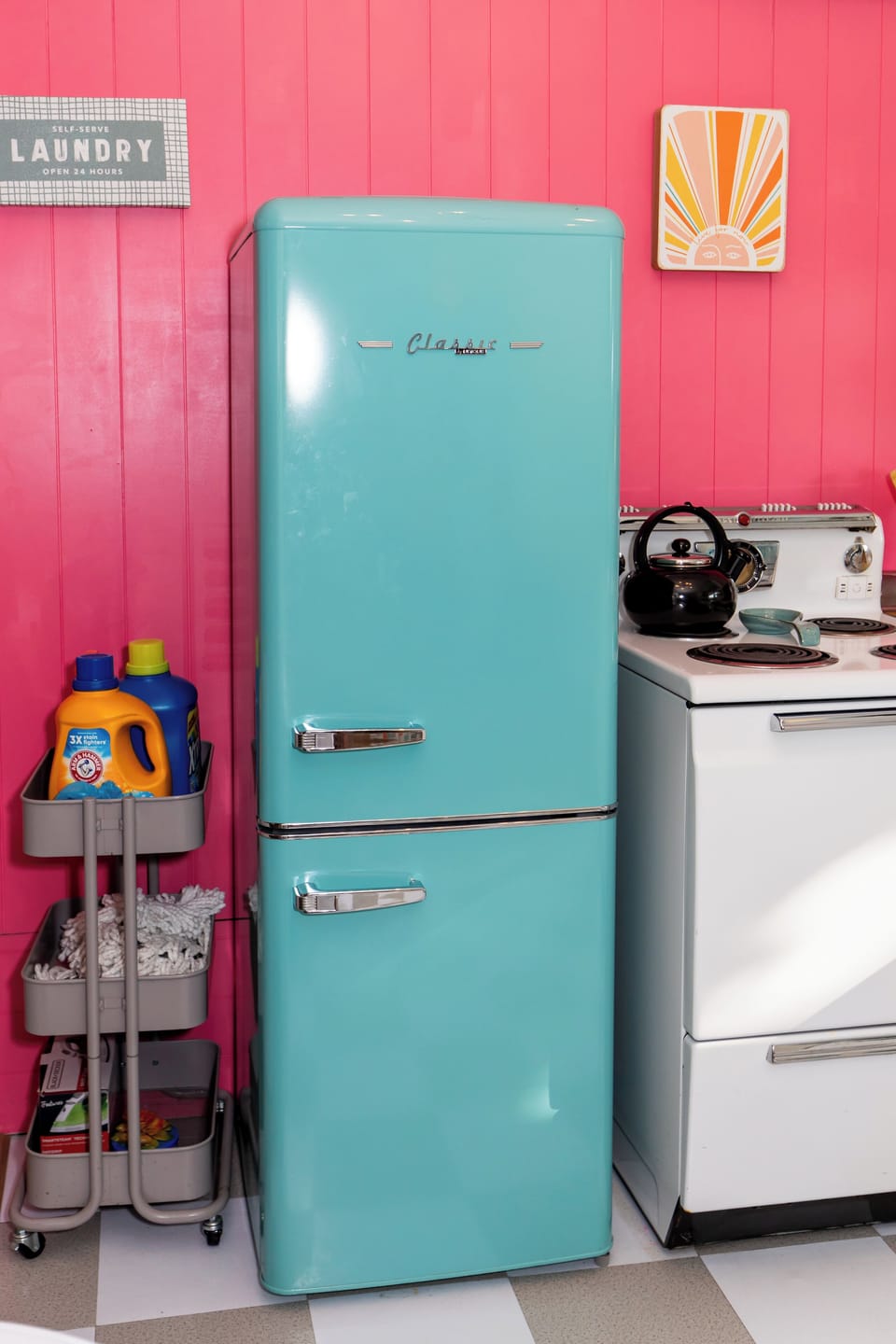 This charming turquoise refrigerator adds retro flair to your kitchen space, perfectly complementing the vibrant coral walls for a delightfully colorful cooking experience.