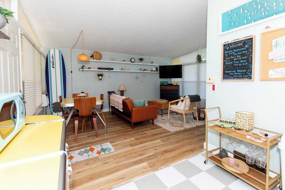 Your stylish living space blends mid-century charm with modern comfort, featuring warm wood floors and coastal-inspired decor.