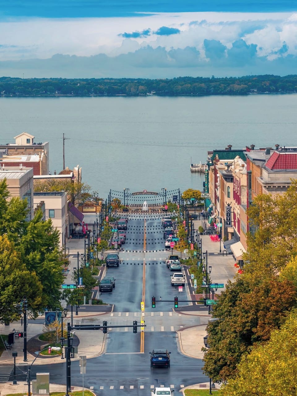 Charming downtown street leads directly to scenic lakefront with colorful buildings and peaceful waters beyond.