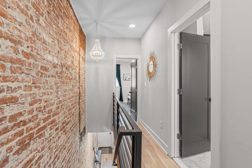 Industrial charm meets elegance in this bright hallway accented by exposed brick and a statement chandelier.