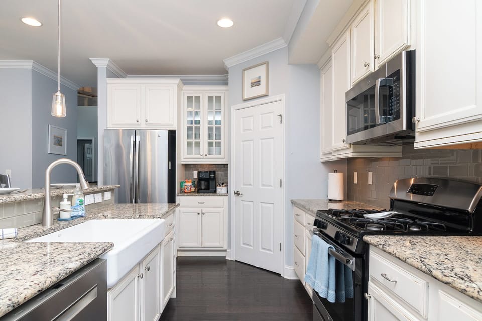 This well equipped kitchen includes granite countertops and a farmhouse sink. 