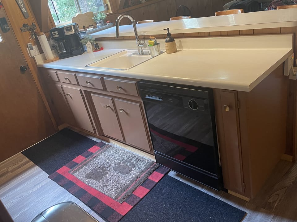 Dishwasher, Coffee Maker, Sink, Door to access deck with BBQ and outdoor table.