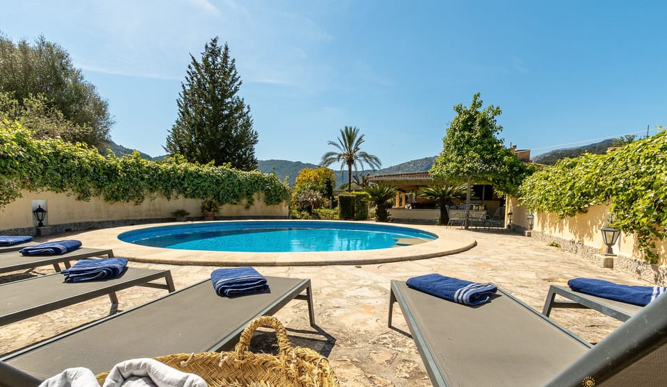 Private pool with sun loungers and towels, surrounded by greenery and mountain views at La Sort Llarga, Pollença.