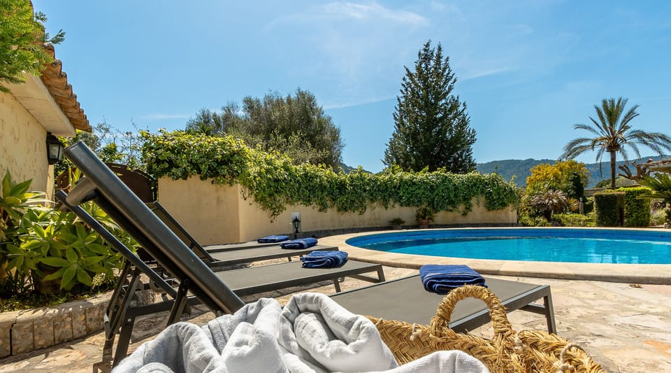 Private pool with sun loungers and towels, surrounded by greenery and mountain views at La Sort Llarga, Pollença.