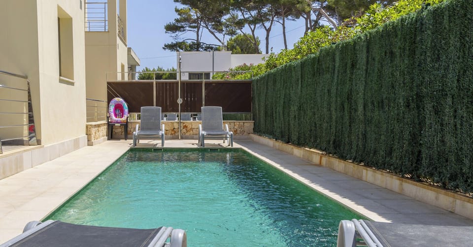 Private rectangular swimming pool at Villa Albufera, with ladder access, sun loungers and hedge fencing ensuring privacy and a relaxing atmosphere.