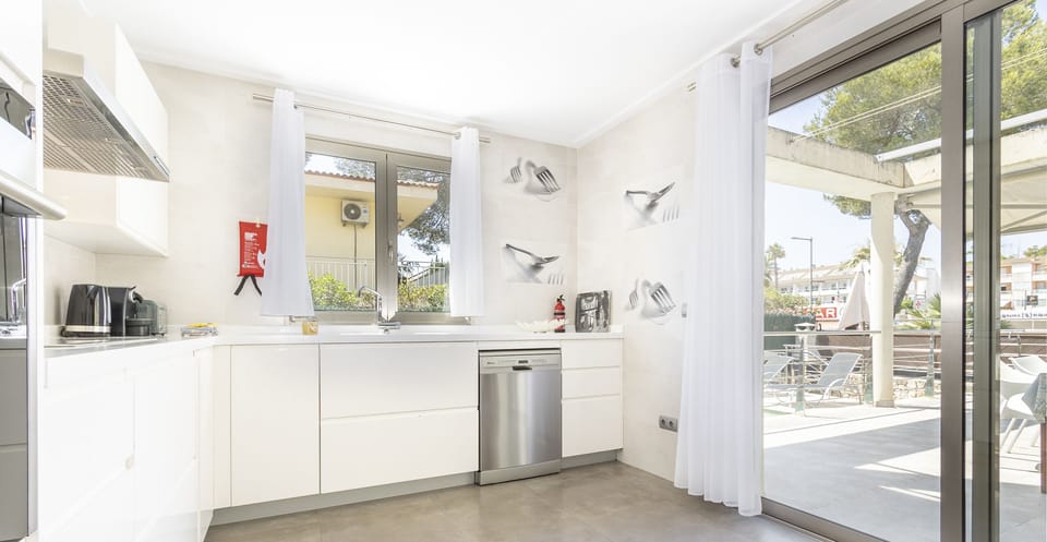 Bright and modern kitchen at Villa Albufera, fully equipped, with direct access to the outdoor terrace, large windows and a functional design ideal for comfortable stays in Mallorca.