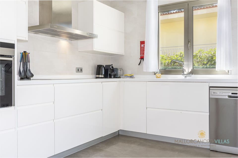 Modern and fully equipped kitchen at Villa Albufera, featuring a white design, spacious worktops, integrated appliances and natural light, perfect for a comfortable and practical stay in Mallorca.