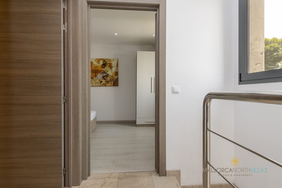 Bright hallway leading to a bedroom in Villa Iola, Playas de Muro, featuring modern finishes and a functional design.