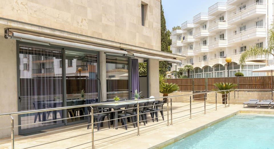Outdoor area of Villa Iola in Playa de Muro featuring a private swimming pool and a spacious terrace with outdoor dining area, stainless steel railings and direct access from the living room.