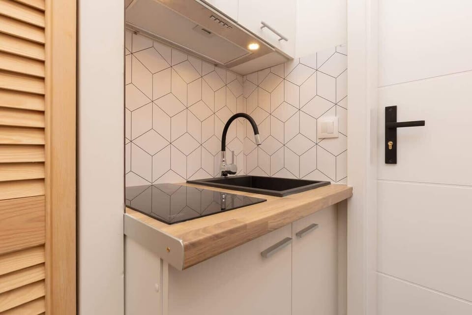 A compact kitchen with wooden countertops, white cabinets, and a black faucet.

