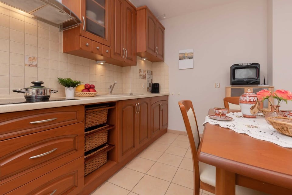 A traditional-style kitchen with wooden cabinets and a dining area, equipped for home-cooked meals.
