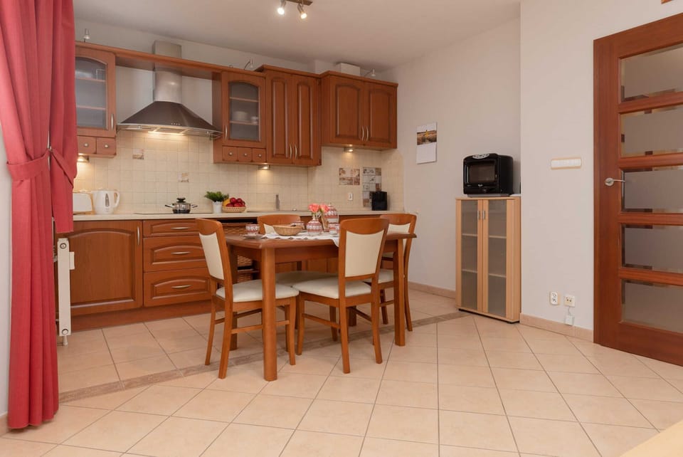 A warm and inviting dining area with wooden furniture and a fully equipped kitchen in the background.
