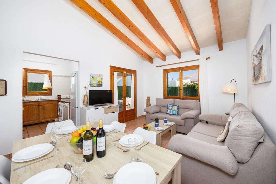Open-plan living room with sofas, dining area, kitchen, A/C, WiFi internet, and satellite TV