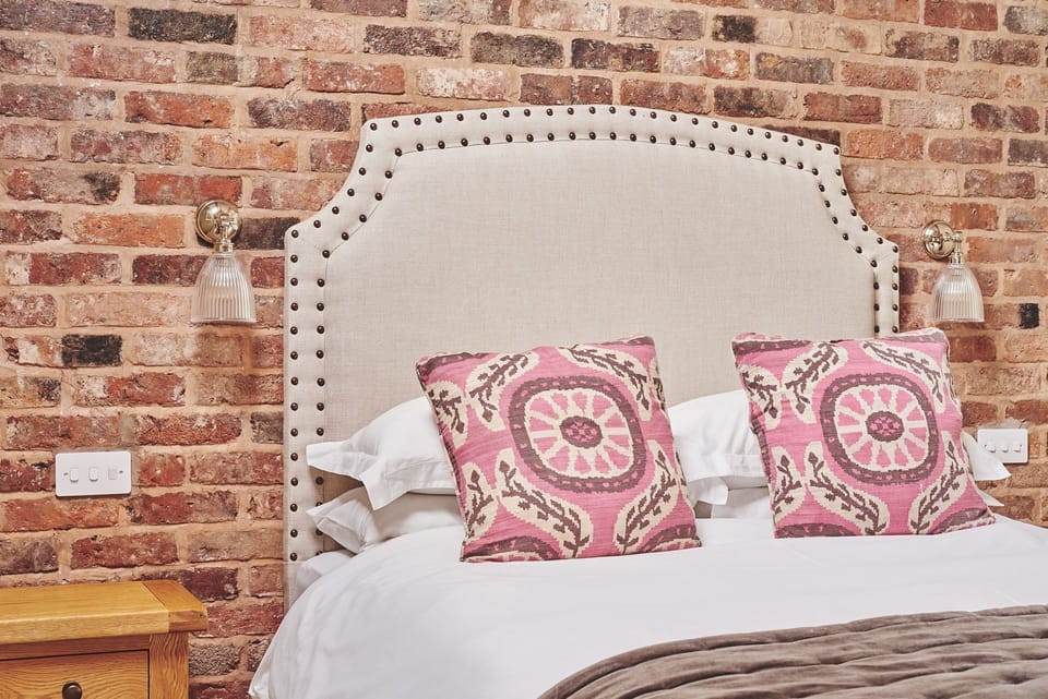 The king-size bed against the exposed brick wall at The Dairy Barn, Worcestershire