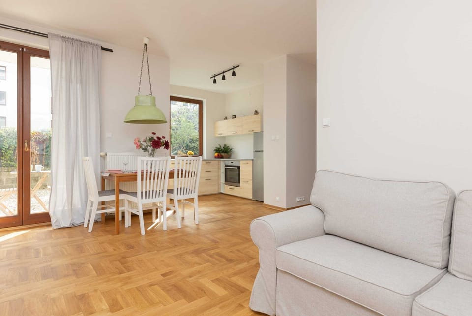 Spacious living room featuring a comfortable sofa and a wooden dining area.
