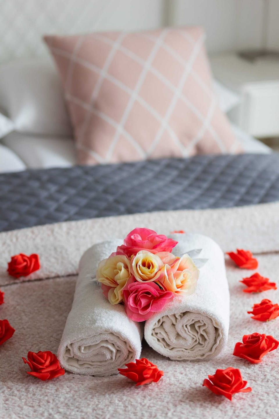 A close-up of a beautifully arranged bed with soft pink cushions and towels.
