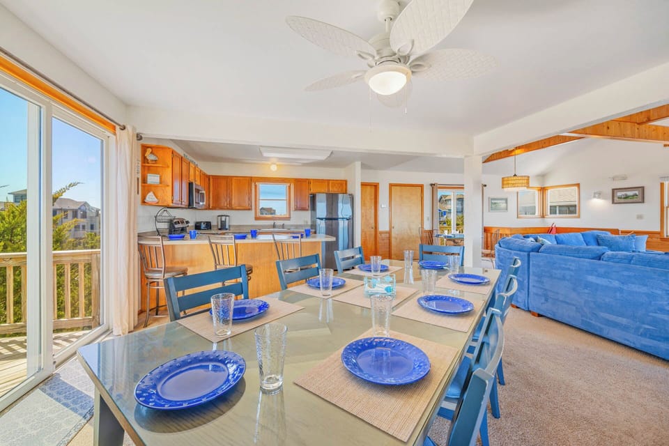 Gather around this bright, open dining space where cheerful blue place settings invite you to share meals and make memories with your group, all while enjoying coastal breezes and natural light.