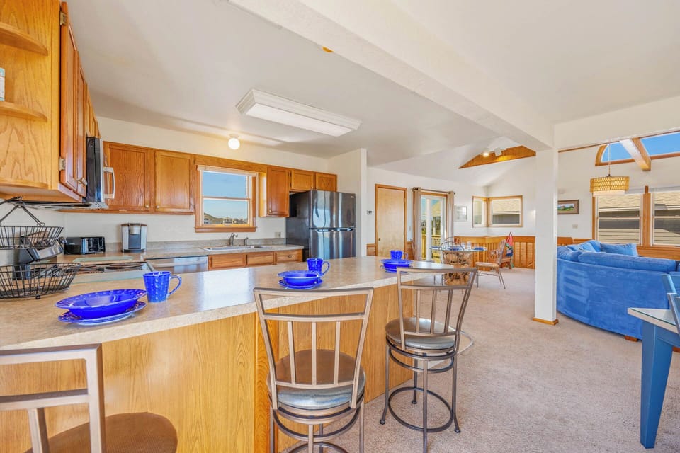 Step into your open-concept retreat with soaring vaulted ceilings and sunlight streaming through multiple windows. The full kitchen and breakfast bar flow seamlessly into the spacious living area—perfect for relaxing or gathering with loved ones.