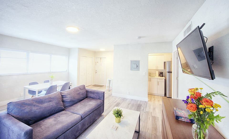 Featuring living room with 40" smart TV, and sofa queen bed. Apartment entry and kitchen entry in view.