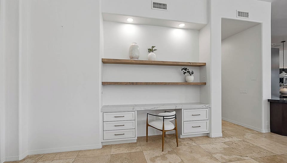 Work desk with shelves near kitchen & living room for a convenient workspace.