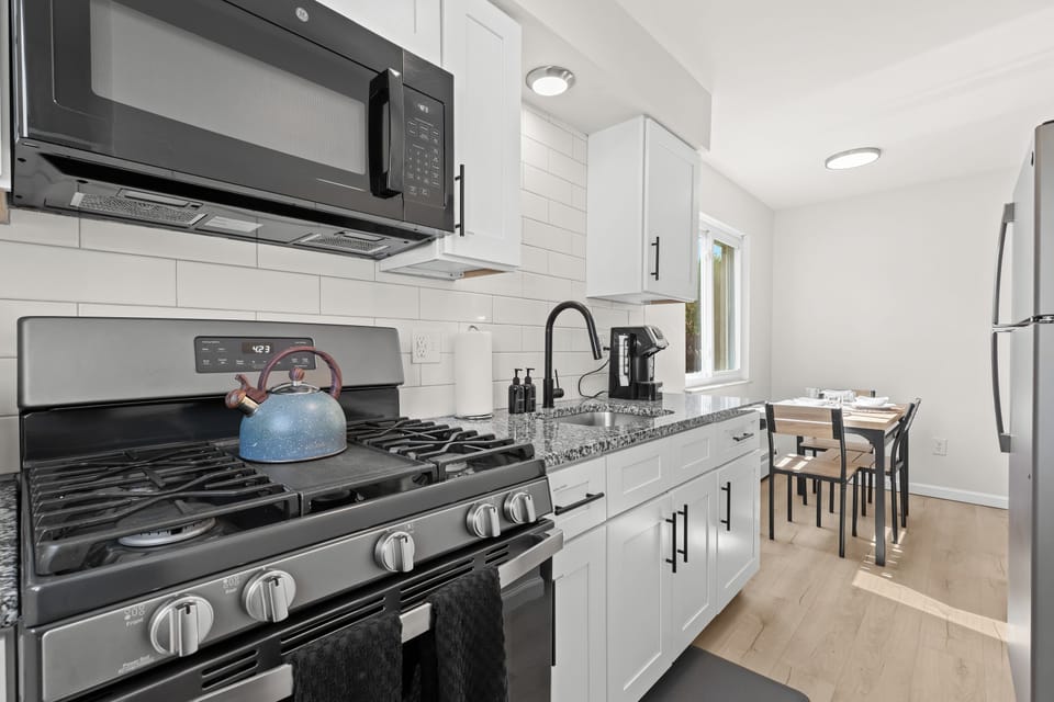 This bright and contemporary galley kitchen features granite countertops, stainless steel appliances, and a cozy dining nook bathed in natural light — perfect for enjoying meals at home.