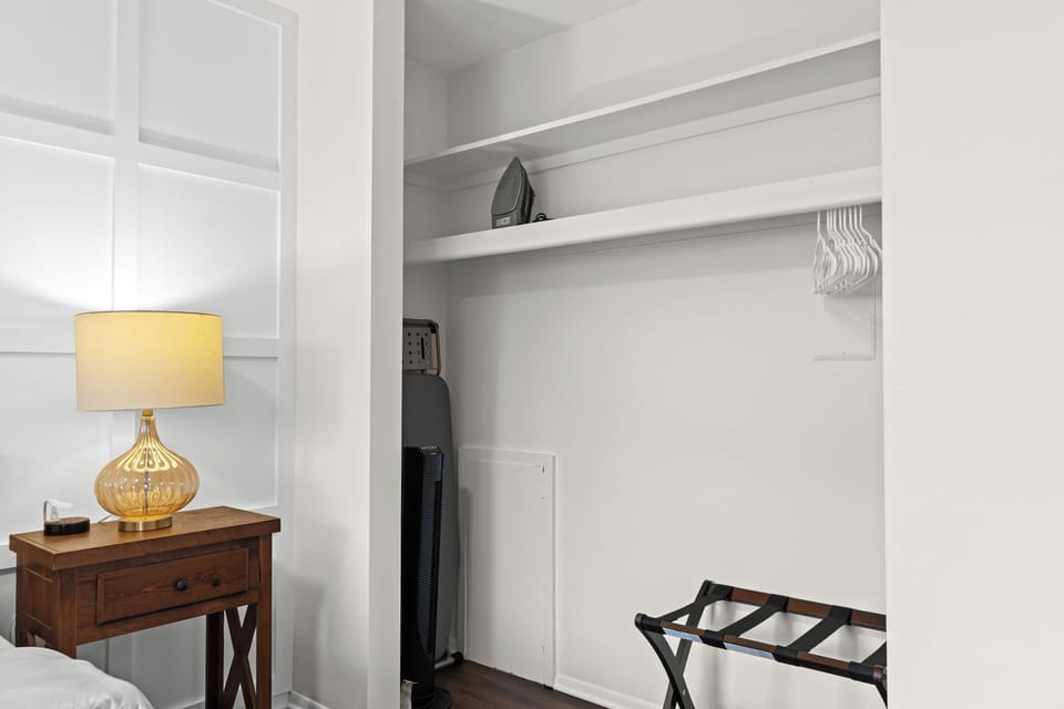 Spacious closet area equipped with hangers, ironing essentials, and a luggage rack—perfect for short or long stays