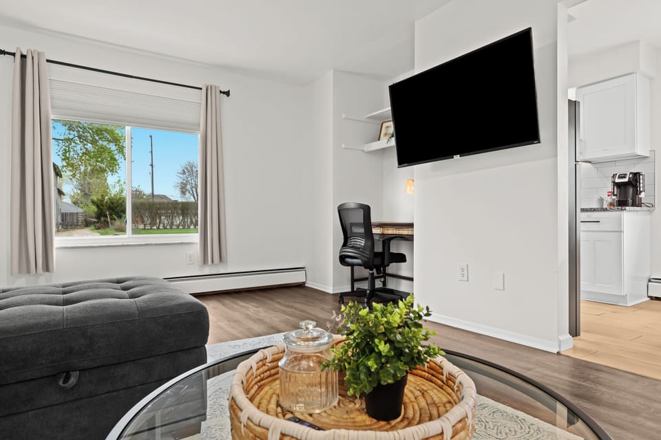 Bright and modern living space with cozy seating, smart TV, and dedicated workspace—perfect for relaxing or working remotely.