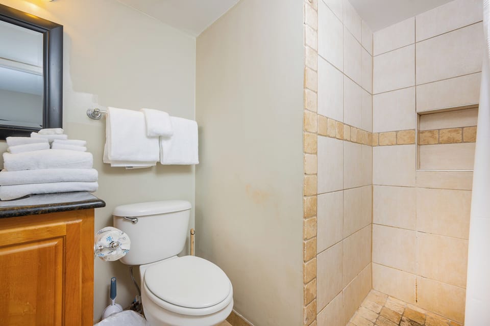 Stacked towels await your refresh after a warm shower in the guest bath with textured tile accents
