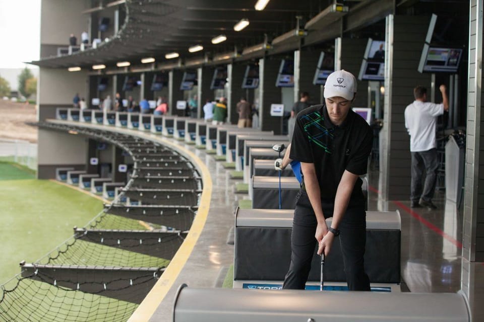Golf driving range with multiple bays and players.