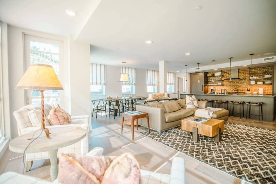 The beautiful living space in the loft-like, open-concept living, kitchen and dining room features a fireplace, large flat-screen TV, a leather sectional sofa, ottomans and two plush armchairs with views of Main Street below.