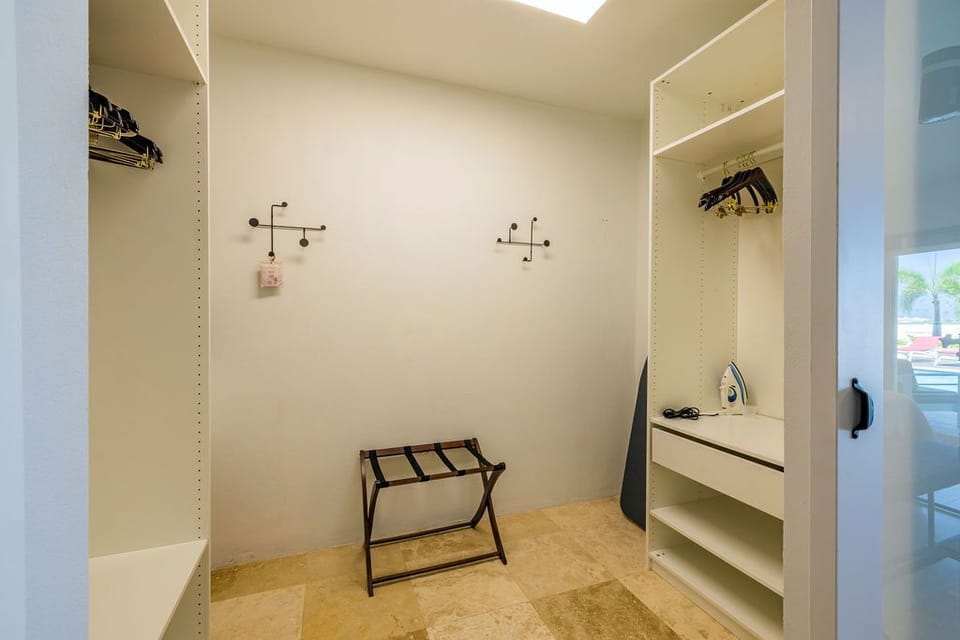 Your personal walk-in closet features generous hanging space, built-in shelving, and a convenient iron—perfect for keeping your wardrobe fresh and organized during your stay.