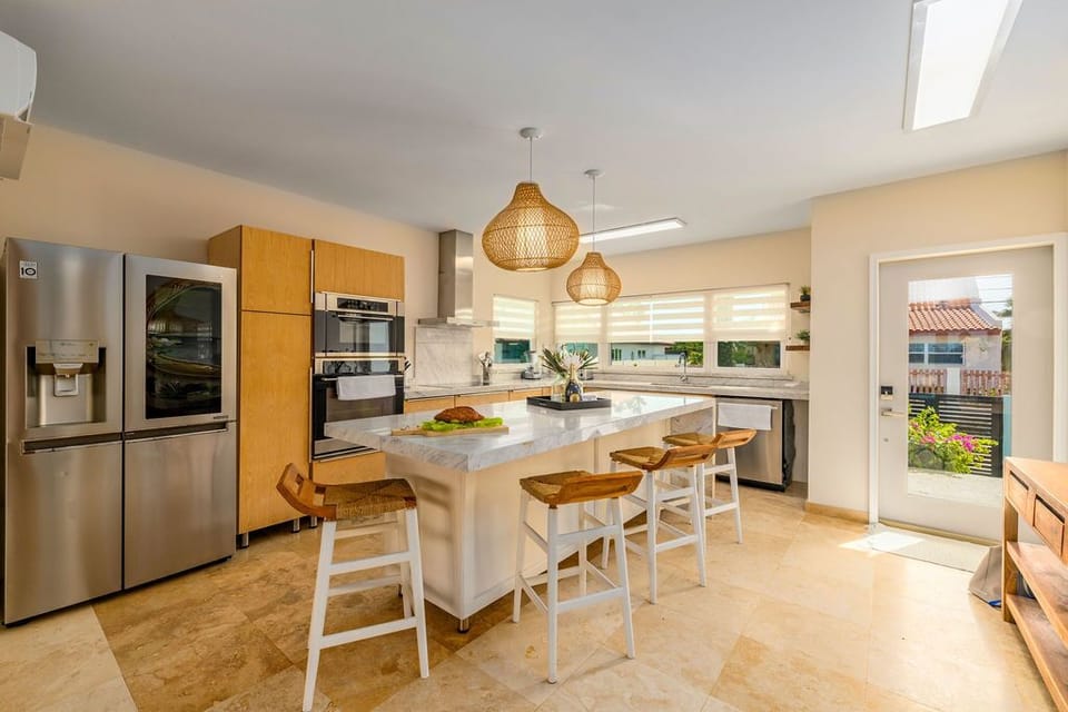 Step into your fully equipped kitchen featuring stainless appliances, marble island with seating for casual meals, and warm pendant lighting that creates an inviting space for gathering with loved ones.