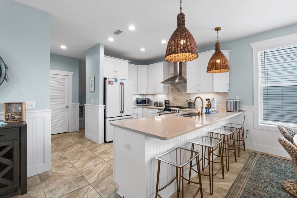 Your spacious kitchen features white cabinetry, modern stainless steel appliances, and a generous island with seating—perfect for prepping meals or gathering with loved ones over morning coffee.