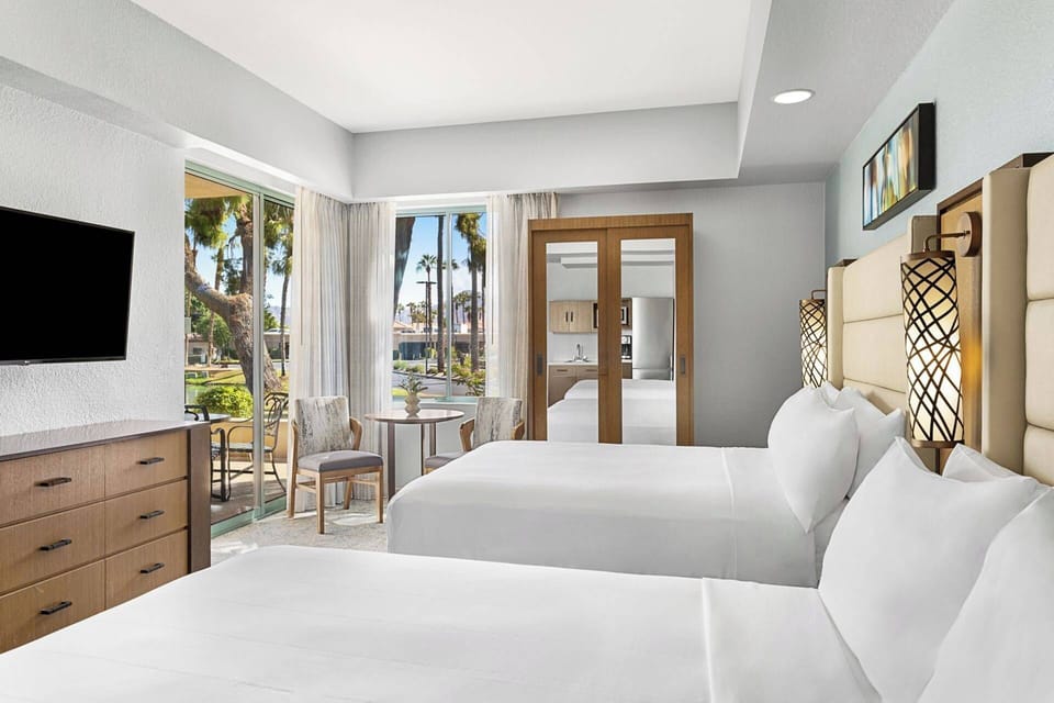 Guest Bedroom features two queen beds, dining table for two, kitchenette, and door to the balcony