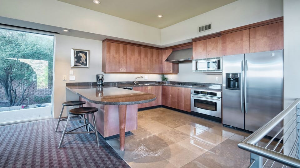 Modern casita kitchen with dark stone counters, gas stove, and seating.