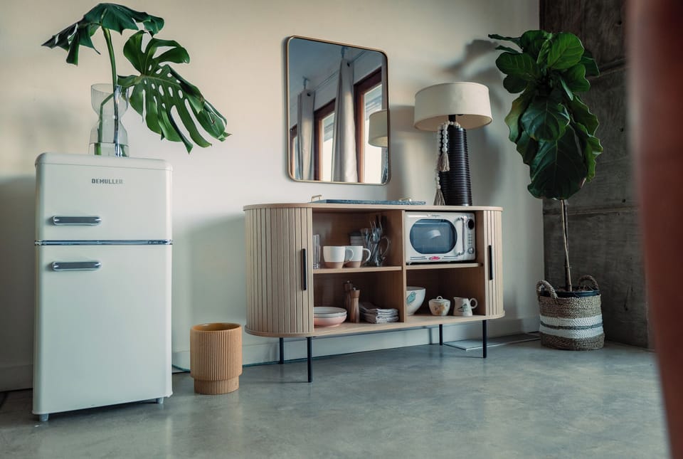 Mini Kitchenette with mini fridge, microwave, dishes and silver, cooktop .
