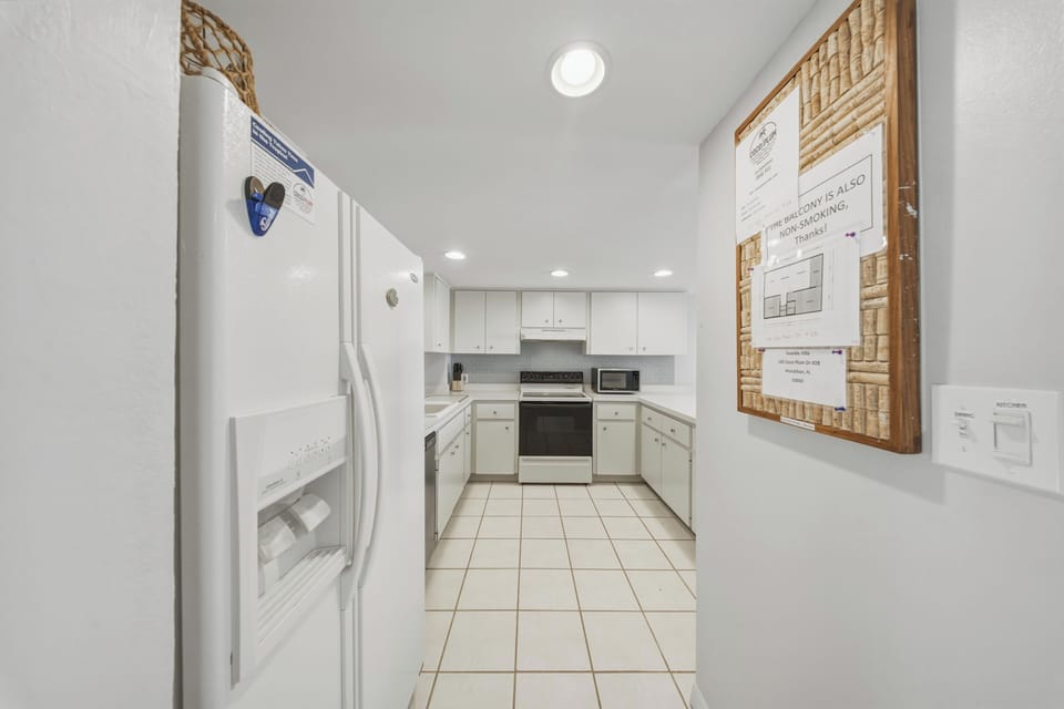 White cabinetry, full-size appliances, and generous workspace provide a bright and functional kitchen designed for easy meals and vacation living.