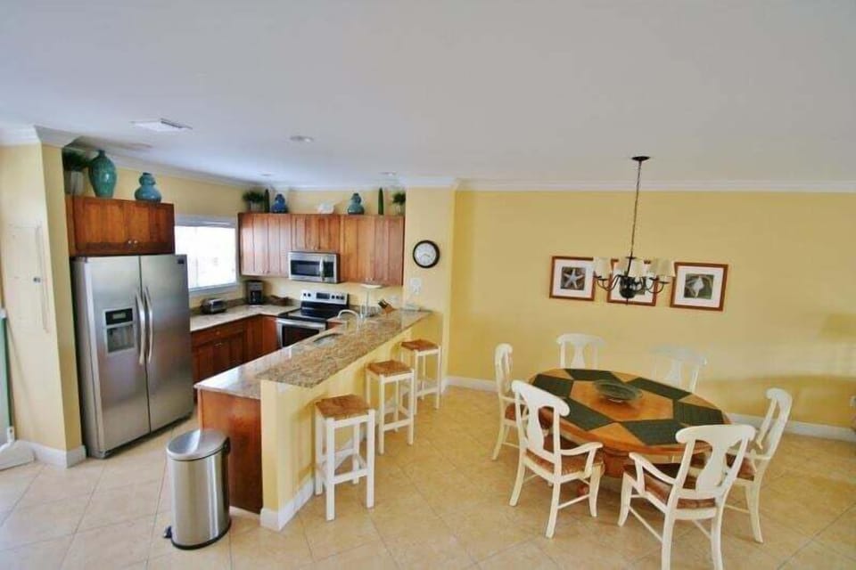 Open-concept dining area with seating for six, seamlessly integrated with a fully equipped kitchen featuring bar stools.