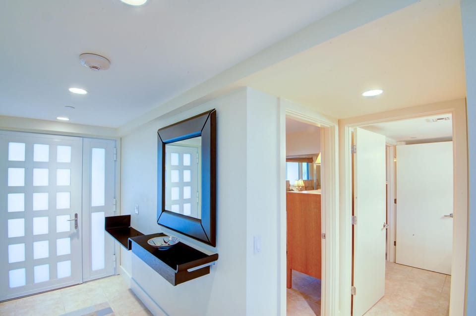 Entryway with frosted glass double doors, floating black console table, and a large dark-framed mirror.
