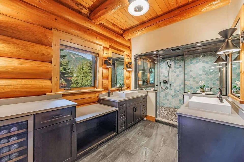 Rustic elegance in a spacious bathroom with log cabin walls, modern fixtures, and mountain views.
