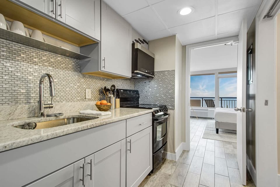 Modern kitchen with sleek cabinetry and a stylish blue-tile backsplash, fully equipped for your culinary needs. Just steps from the bedroom, this space offers convenience and functionality, allowing you to enjoy meals with a stunning ocean view.