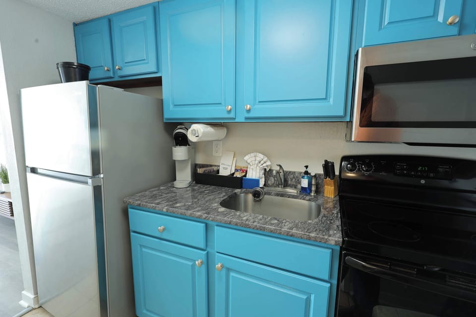Compact and cheerful kitchenette with bright coastal-blue cabinets, full-size appliances, a Keurig, and the essentials for easy meals during your Myrtle Beach stay.