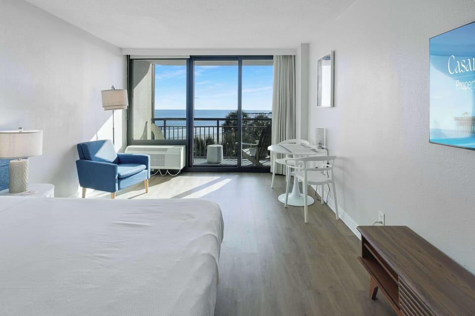 Bright ocean-view studio with a comfortable bed, cozy seating, dining space, and private balcony — a relaxing Myrtle Beach escape just steps from the water.