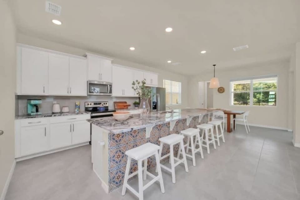 - Open kitchen with large island and bar seating
- Fully equipped space for group meals and hosting
- Bright modern design near dining and living areas
